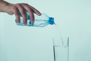 Pouring glass of water from a plastic bottle