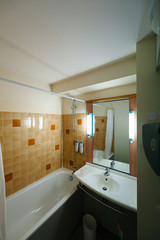 Interior of tiny hotel bathroom with clean bathtub, sink - wide angle lens