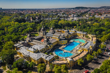 Naklejka premium Budapest, Hungary - Aerial drone view of the famous Szechenyi Thermal Bath and Spa on a sunny summer day. Heroes' Square and Vajdahunyad Castle at background.