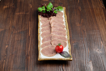 Beef tongue sliced in thin slices on a plate on a brown rustic background. restaurant menu