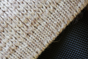 A fragment of a cozy Scandinavian sweatshirt. Gray knitted woolen fabric on a black background. Warm clothes for winter and autumn cold
