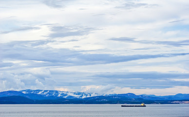 Fototapeta na wymiar An empty tanker ship sails through the Inside Passage of Alaska on a stormy day.