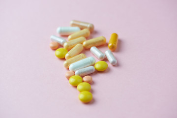 Vitamins on pink paper background. Concept for a healthy dietary supplementation. Close up. Copy space. 