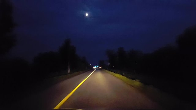 Driving Through Rural Countryside Approaching City Lights on Horizon.  Driving Point of View POV Driving Towards Entering Urban Limits at Night.