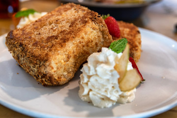 Plate of french toast served with sliced fruits and creme fraiche