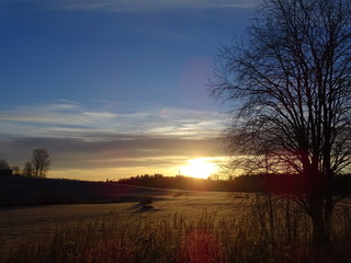 Fototapeta na wymiar Sunrise over a Finnish field and forest in autumn 