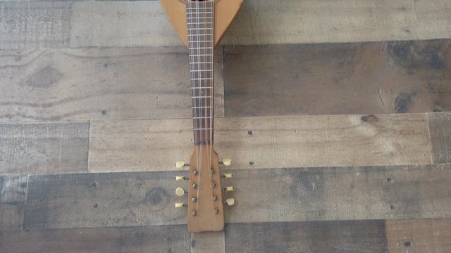 Panning across wood stringed ukulele instrument. Slow closeup, 4k, flat lay.