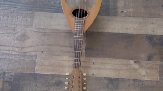 Stringed wood instrument, flat lay closeup pan, on brown wooden background.