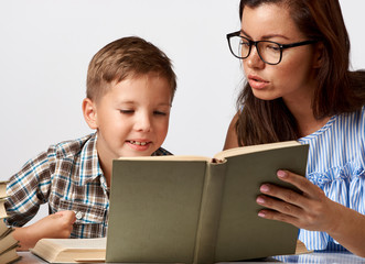 Teacher and young boy reading book over white background