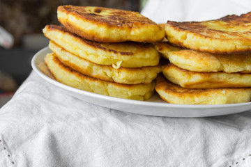 Stack of homemade mascarpone pancakes fritters on plate on white cotton tablecloth. Breakfast setting cozy homely atmosphere rustic style