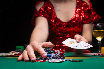 Casino games. A girl in a red evening dress and plays poker in a night casino. opens cards and takes winnings
