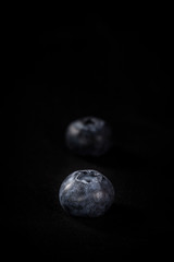 Two blueberries isolated on black background with space on above for copy