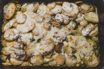 plant-based potato and veggies bake with vegan cheese topping and herbs