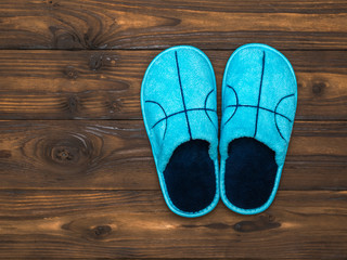 Blue Slippers on the dark brown wooden floor. The view from the top. Flat lay.