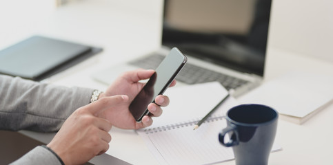 Close-up view of young businessman collecting informations for his project on his smartphone