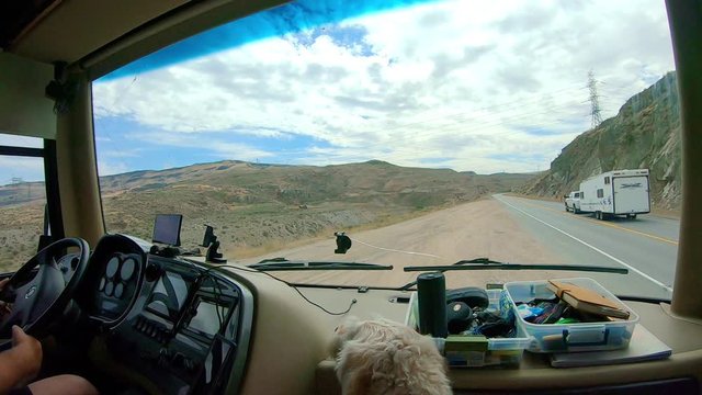 POV of the passenger in a large class A Recreational Vehicle while merging back on to the highway the Okanogan Highlands of north central Washington State with a labradoodle dog in the foreground