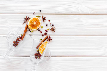 Mulled wine concept. Spices and dried orange in glasses on white wooden background top view space...