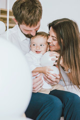 Happy young real family celebrates baby's first year at home in bright interior