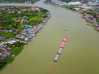 Aerial view of the large cargo ship on the Chao Phraya River with cityscape, The river with green water in rainy season, Copy space, Top view, Bangkok, Thailand.