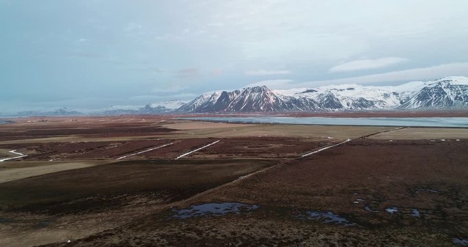 Flying Fantom 4 pro Drone in Iceland shoting frozen lake at sunrise near the mountains