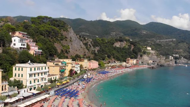 In Monterosso or La Spezia, this drone shot starts along the beach and flies up, out towards the ocean, pans left, and tilts down altogether in a smooth manner.