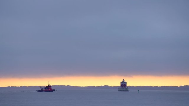 Red Tug Boat Passes Through The Harbor Near Ledge Lighthouse on a Gloomy Morning