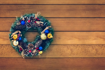 Christmas wreath handmade on a wooden background. Festive lights of garland. New Year's interior decoration. copy space for text.