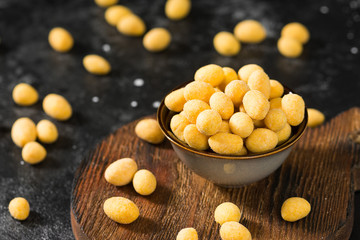 Peanuts in cheese sauce in a dark bowl on a black table