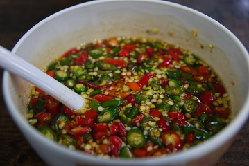 Colorful chili slice is flaoting on fish sauce in a white porcelain bowl