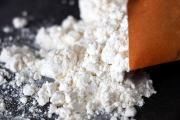 close-up flour spilled from a bag on a dark background. White flour