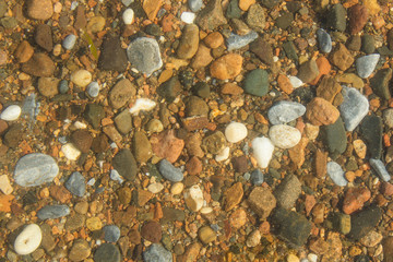 On Lake Baikal, through clear water, small colored stones are visible.