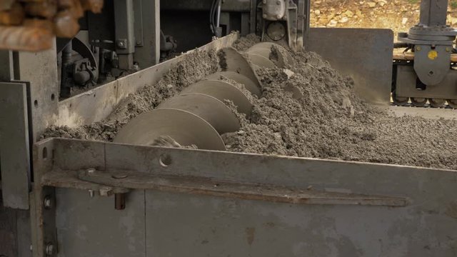 Fully mechanised process of concrete pavement construction. The slipform paver spreads the concrete over the full paving width with its auger. Preparation for laying a base layer. Shot right to left
