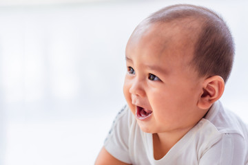 Fototapeta premium Asian male baby wearing a white shirt, about six months old, smiling cutely on a white background.