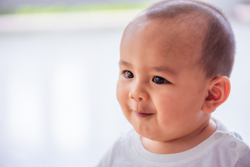Asian male baby wearing a white shirt, about six months old, smiling cutely on a white background.