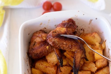 Delicious fried spicy chicken wings whit roasted potatoes/ Closeup still life food photography