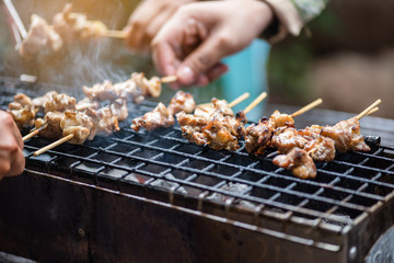 People standing toast, grilled chicken and pork on the stove with smoke in the celebration.