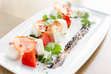 Italian traditional caprese salad. Fresh Salad with tomatoes, basil, mozzarella, and olive oil on wooden background. Mediterranean, natural and organic food concept.