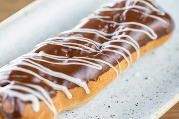 Traditional french eclairs with chocolate. Cake decorated with chocolate cream on top of are on a wooden table
