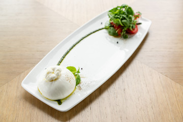 Fresh Salad with tomatoes, basil, burrata, and olive oil on wooden background. Italian traditional caprese salad. Mediterranean, natural and organic food concept.
