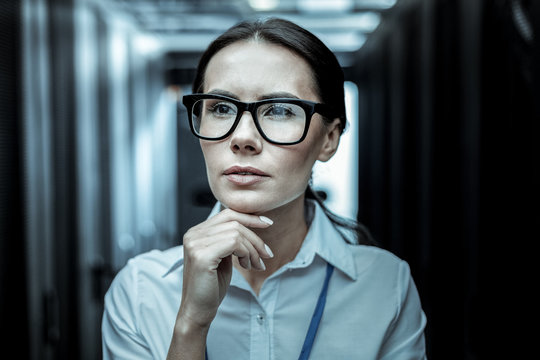 Dark-haired professional from intelligence agency in eyeglasses looking thoughtful