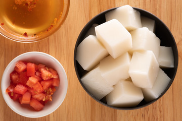 Tofu Jelly in bowl on wooden background,Diced tomatoes in a cup,Top view