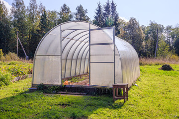Fototapeta na wymiar Greenhouse. Bright greenhouse in the garden. Indoor stationary greenhouse