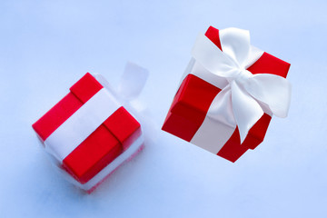 winter holiday card or sale poster with gift box frozen in ice and red gift box with festive white satin ribbon with bow