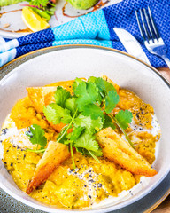 A bowl of vegetarian Dhal with flatbread and garnished with coriander
