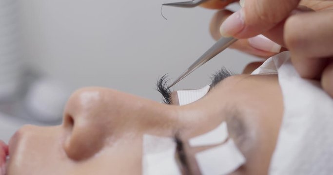 Female having eye lash extension in beauty salon