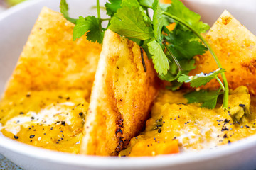A bowl of vegetarian Dhal with flatbread and garnished with coriander