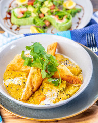 A bowl of vegetarian Dhal with flatbread and garnished with coriander