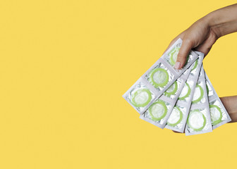Close-up woman holding wrapped green condoms