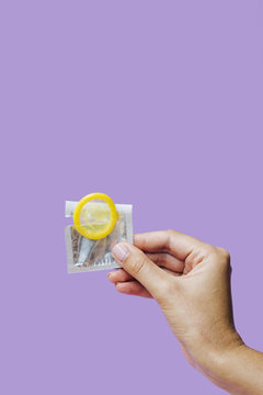 Close-up hand holding yellow condom