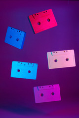 Colored audio cassettes hanging in the air against purple background